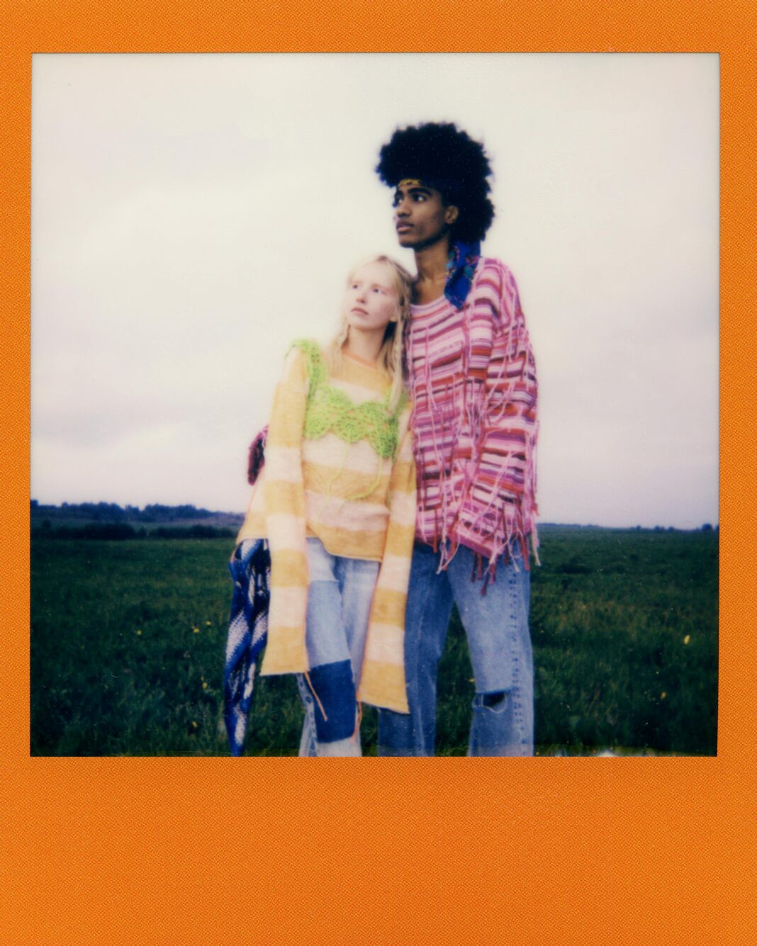 indie Młoda para w kolorowych ubraniach w stylu bohemy obejmująca się na wiejskiej łące.