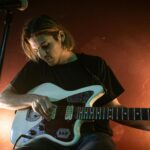 Muzyk grający na gitarze elektrycznej w barze z ciepłym oświetleniem.