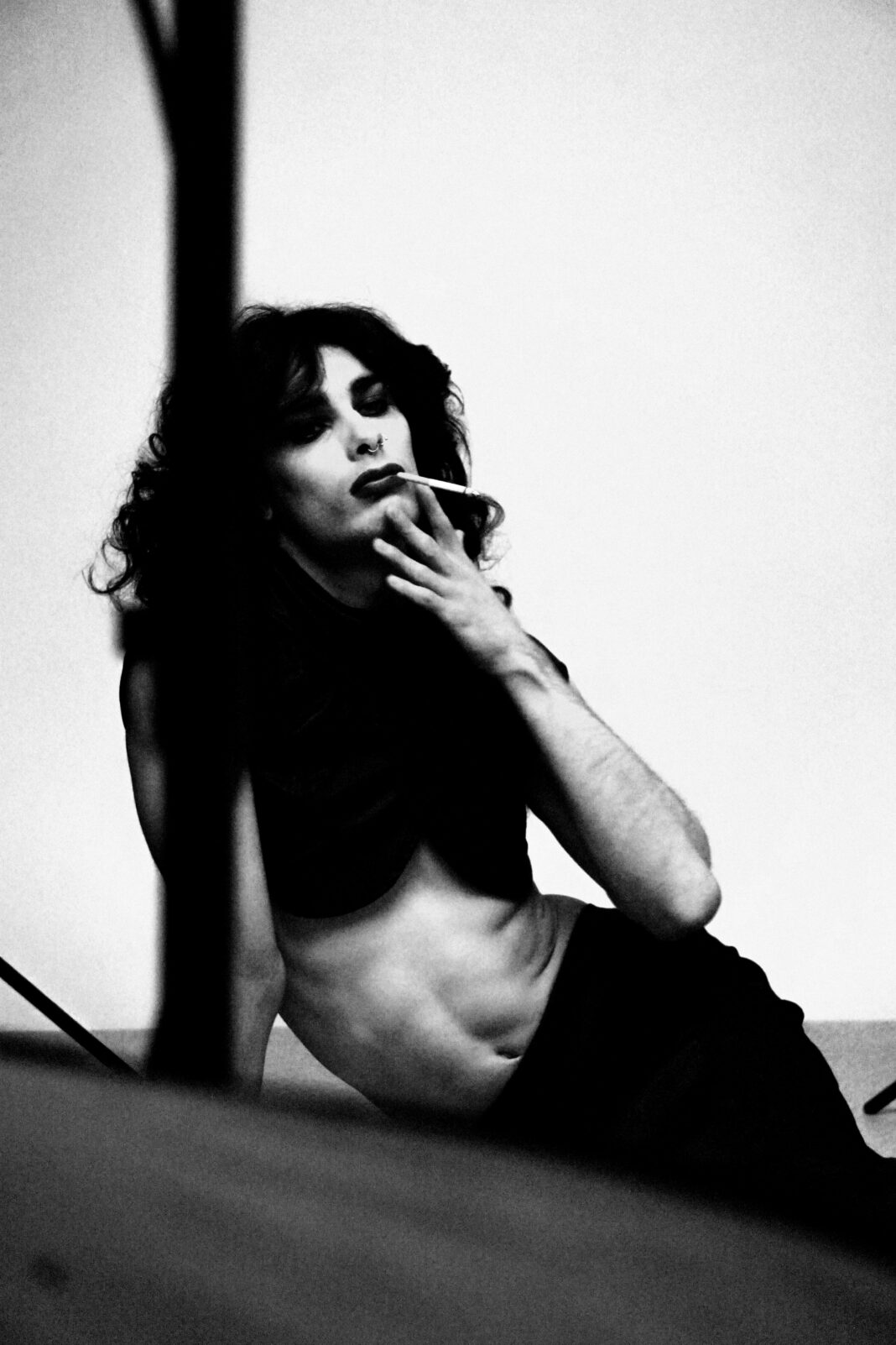 Nastrojowy czarno-biały portret osoby w artystycznej pozie z papierosem