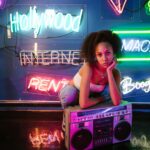 Młoda kobieta w oświetlonym neonami pokoju z boomboxem w stylu vintage, ucieleśniającym tętniące życiem nocne życie i kulturę miejską.