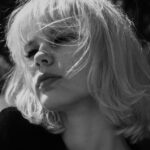 Artystyczny czarno-biały portret kobiety o blond włosach na świeżym powietrzu.