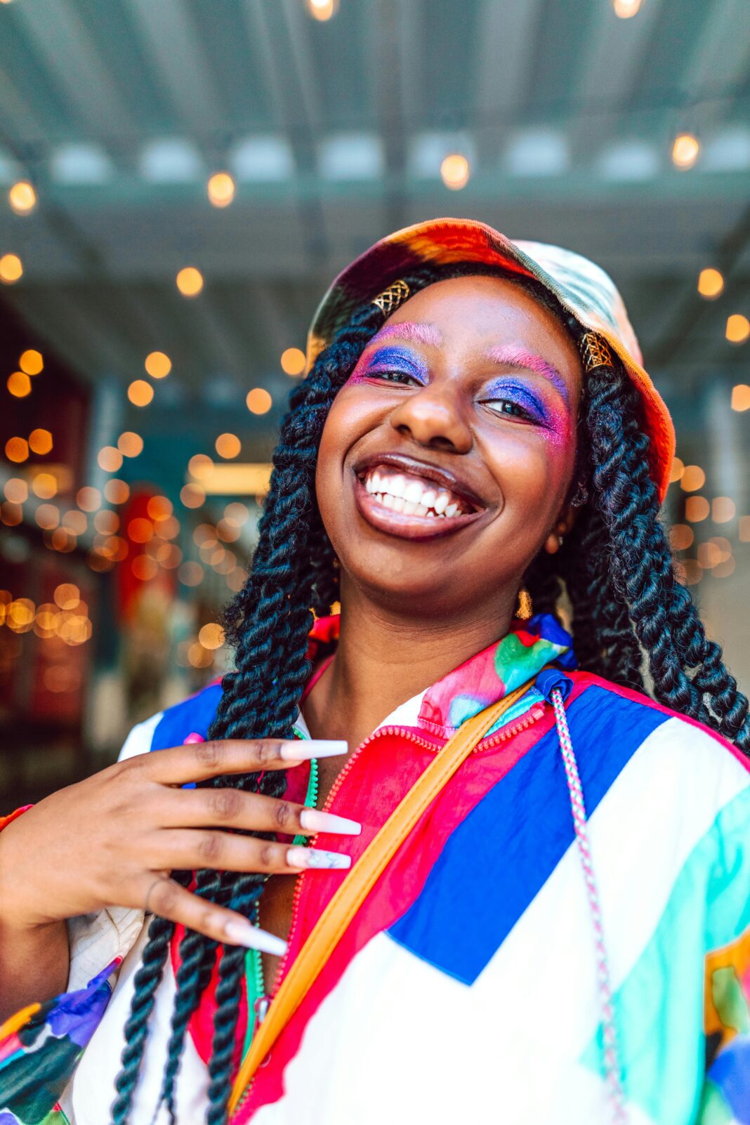 Wesoła kobieta z żywym makijażem i kolorowym ubraniem, emanująca szczęściem.