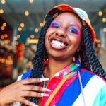 Wesoła kobieta z żywym makijażem i kolorowym ubraniem, emanująca szczęściem.