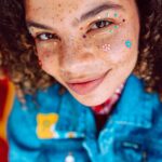 Himalaje w Indiach: Trekking w Ladakhu i Spiti Valley Żywy portret przedstawiający młodą osobę z kreatywnym makijażem twarzy, emanującą młodzieńczą radością i stylem.