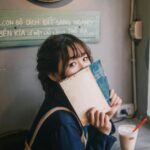 Khajuraho: Świątynie erotyczne – sztuka i symbolika Młoda kobieta w swobodnym stroju lubi książkę i kawę w przytulnej kawiarni.