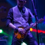 Muzyk z pasją grający na mandolinie na scenie podczas tętniącego życiem koncertu na żywo.