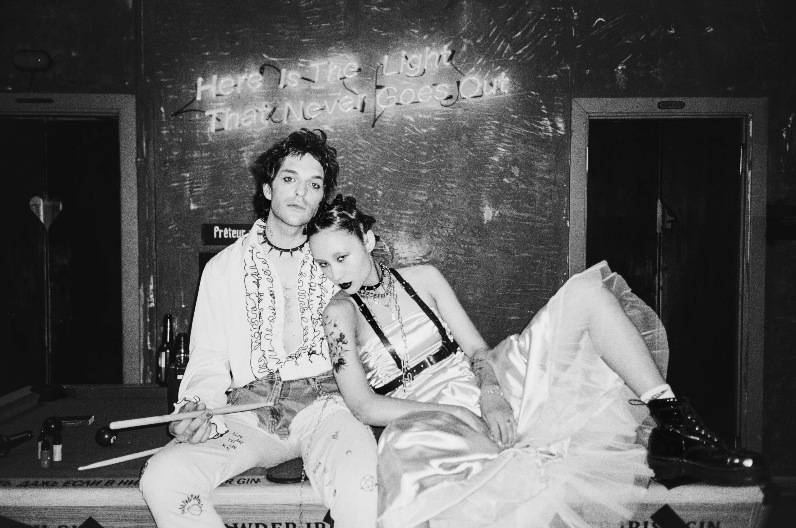 Stylowa para ubrana w wyjątkowe stroje, relaksuje się przy stole bilardowym w nastrojowym pokoju.