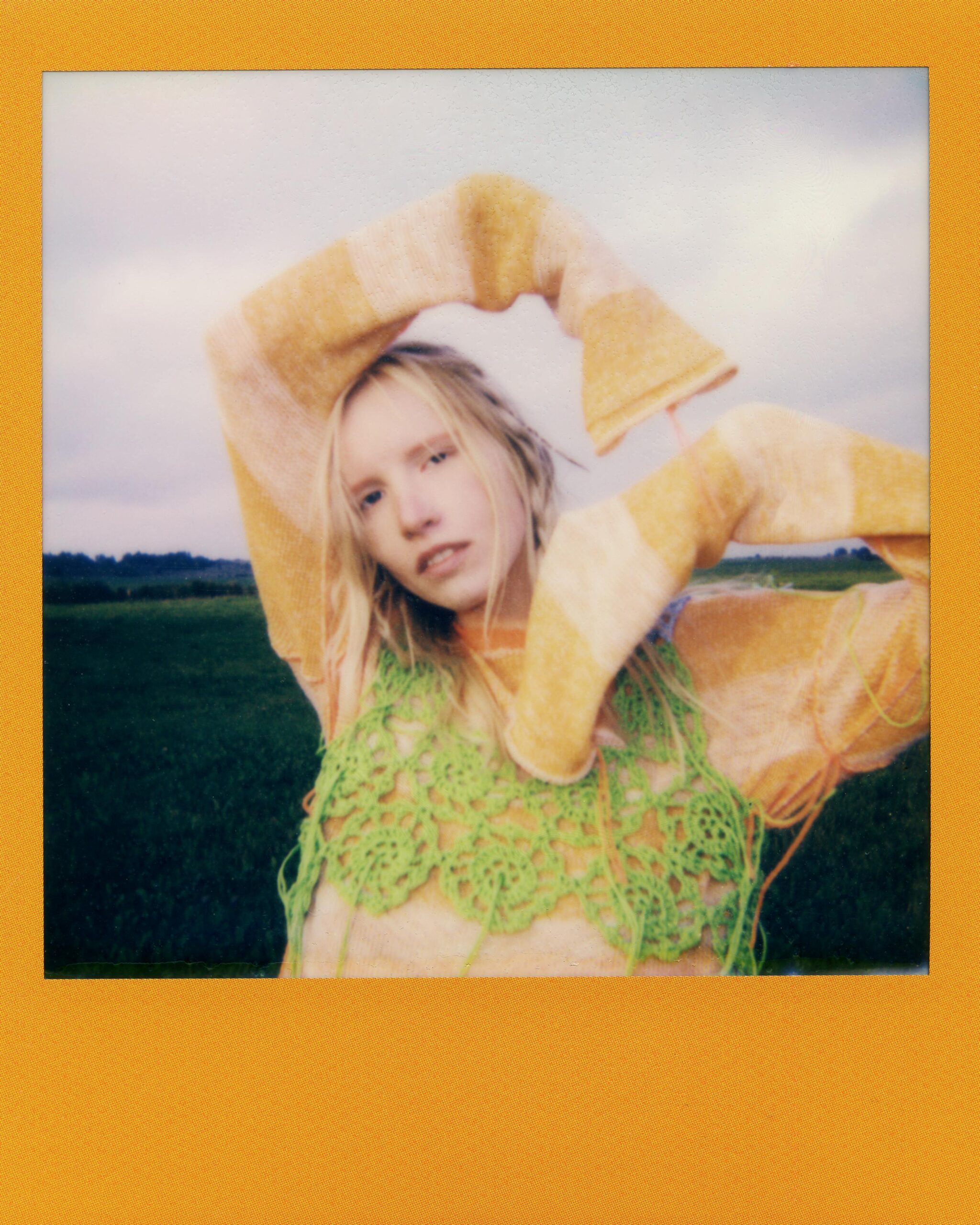 Artystyczny portret kobiety w kolorowym swetrze pozującej na świeżym powietrzu w naturalnym świetle.