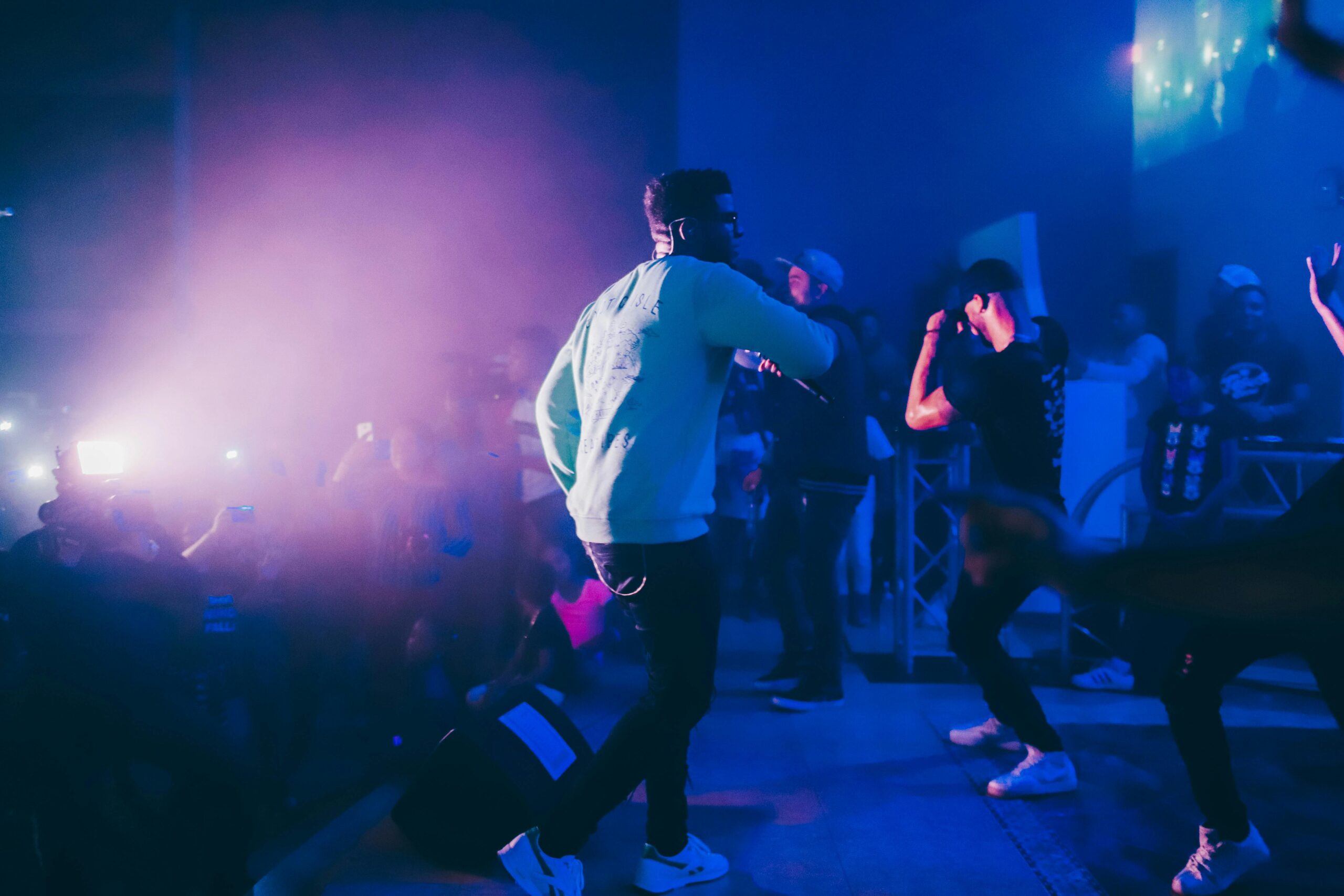 Dynamiczny występ na żywo z raperem na scenie w tętniącym życiem klubie nocnym z entuzjastycznym tłumem.