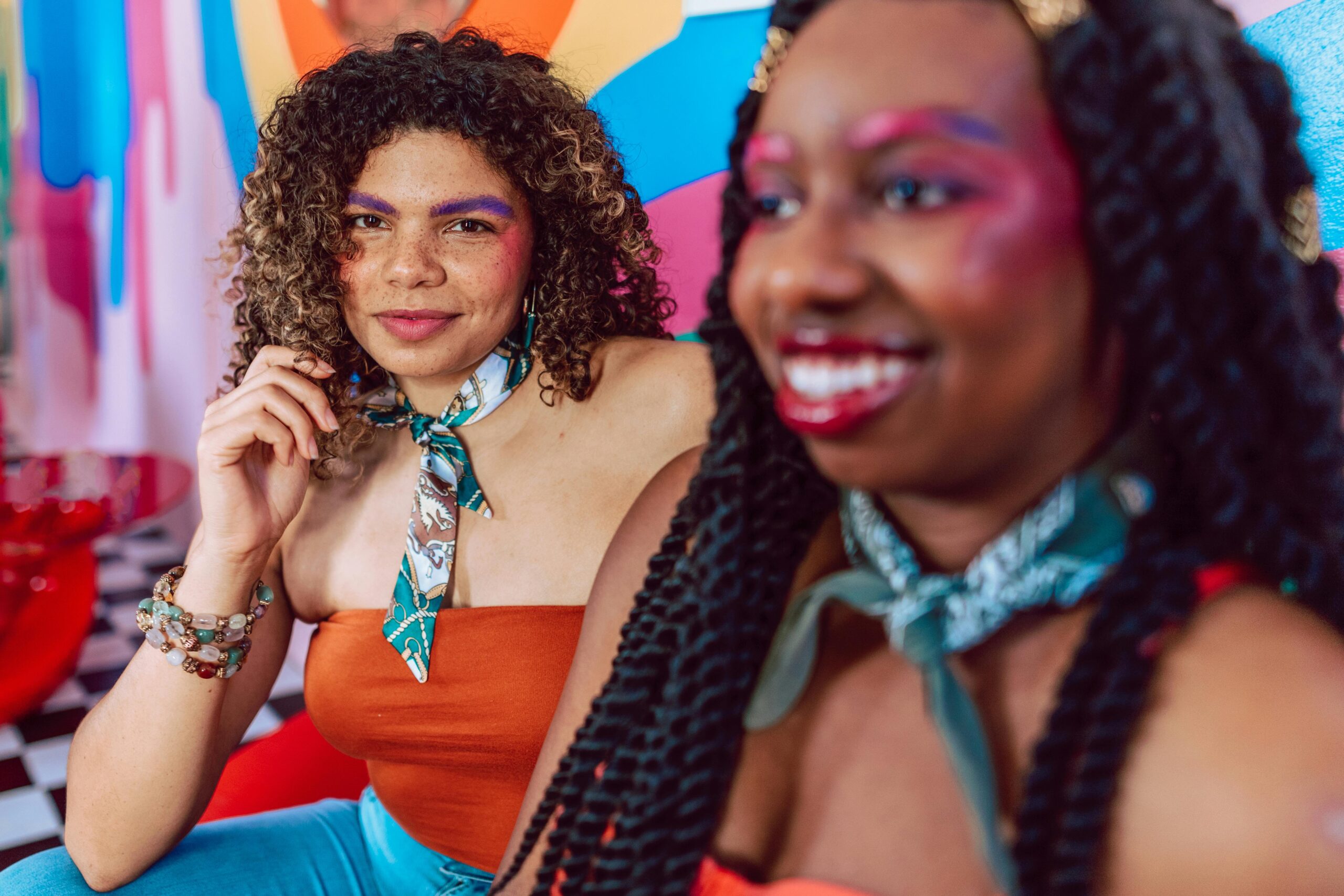 Żywy obraz dwóch kobiet z kolorowym makijażem i radosnymi minami.