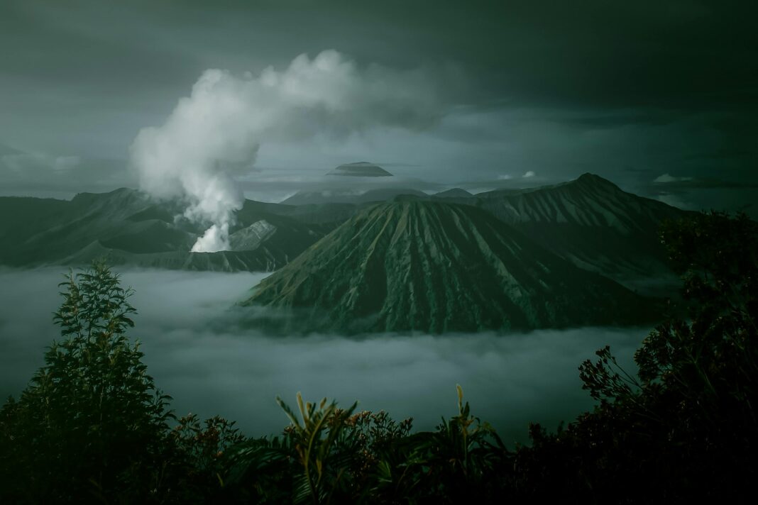 Dramatyczny krajobraz góry Bromo z mgłą i dymem wulkanicznym uchwycony o wschodzie słońca w Indonezji.