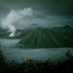 Dramatyczny krajobraz góry Bromo z mgłą i dymem wulkanicznym uchwycony o wschodzie słońca w Indonezji.