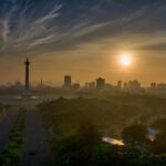 Zapierający dech w piersiach widok z lotu ptaka na panoramę Dżakarty o zachodzie słońca, podkreślający kultowy Pomnik Narodowy.