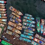 Kolorowe łodzie skupione w doku Penjaringan w Dżakarcie, uchwycone z perspektywy lotniczej.