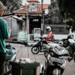 Sprzedawca uliczny w Marga na Bali w Indonezji sprzedaje towary przejeżdżającym motocyklistom. 