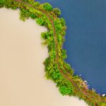 Widok z lotu ptaka na kontrastujące zbiorniki wodne oddzielone bujną zieloną ścieżką w Banten w Indonezji.