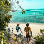 Raja Ampat: Podwodny raj dla nurków i miłośników przyrody Surferzy udają się bujną ścieżką na oszałamiającą plażę na Bali w Indonezji.
