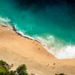 Oszałamiający widok z lotu ptaka na plażę Bali z turkusowymi falami rozbijającymi się o złoty piasek.