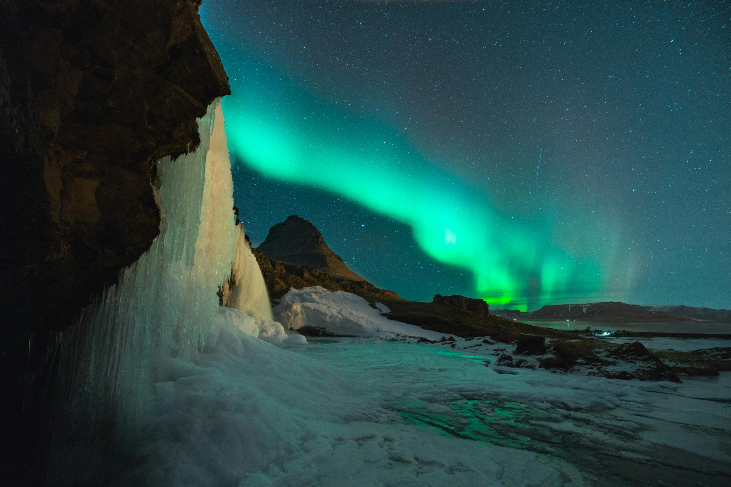 Wspaniały widok na zorzę polarną nad górą Kirkjufell i zamarzniętym wodospadem na Islandii.