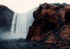 Grupa poszukiwaczy przygód stoi przed majestatycznym wodospadem Skogafoss na Islandii.