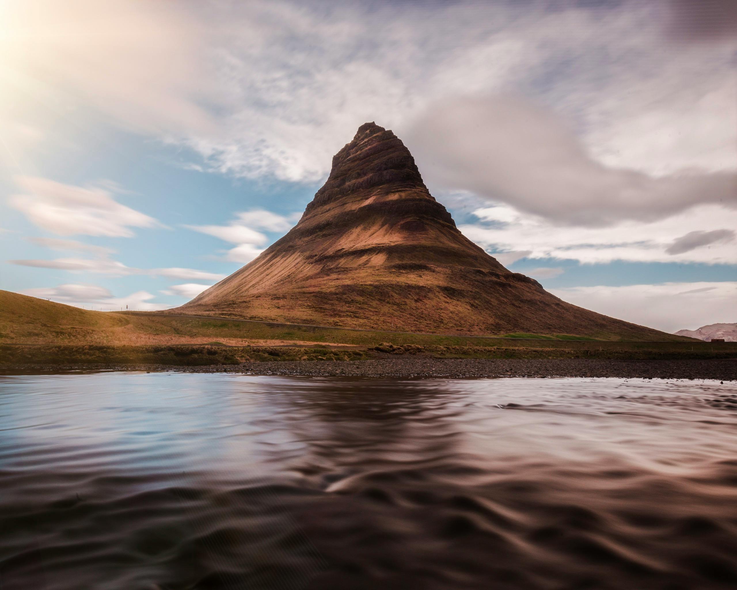 Piękna góra Kirkjufell odbita w wodzie pod pochmurnym niebem na Islandii.