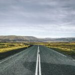 Islandia – czy warto wynająć przewodnika? Prosta droga prowadząca przez malownicze krajobrazy Islandii pod zachmurzonym niebem.
