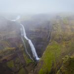 Reykjavik nocą – najlepsze atrakcje i życie nocne Oszałamiający wodospad spływający kaskadą przez skaliste klify w mglistej scenerii Islandii.