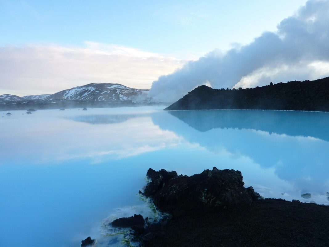 islandia Urzekający widok na Błękitną Lagunę na Islandii z parującymi wodami geotermalnymi i odległymi górami.