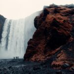 Grupa poszukiwaczy przygód stoi przed majestatycznym wodospadem Skogafoss na Islandii.