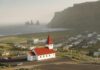 Widok z lotu ptaka na kultowy kościół Vik z czerwonym dachem i kominami Reynisdrangar wzdłuż wspaniałego islandzkiego wybrzeża.