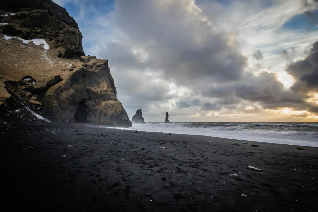 Wspaniały widok na plażę Reyniskirkja z czarnym piaskiem, klifami i falami oceanu w Vík na Islandii.