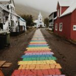 Tętniąca życiem tęczowa ścieżka prowadzi wzrok do malowniczego kościoła w islandzkiej wiosce.