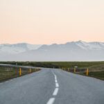 Islandia – TOP 10 atrakcji turystycznych Oszałamiający widok na pustą islandzkią drogę prowadzącą w kierunku majestatycznych gór o zachodzie słońca, idealny do motywów podróży i przygód.