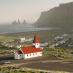 Widok z lotu ptaka na kultowy kościół Vik z czerwonym dachem i kominami Reynisdrangar wzdłuż wspaniałego islandzkiego wybrzeża.