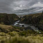 Islandia – jak wygląda system edukacji wyższej? Odkryj zapierający dech w piersiach islandzki krajobraz z nierówną doliną rzeki pod dramatycznym zachmurzonym niebem.