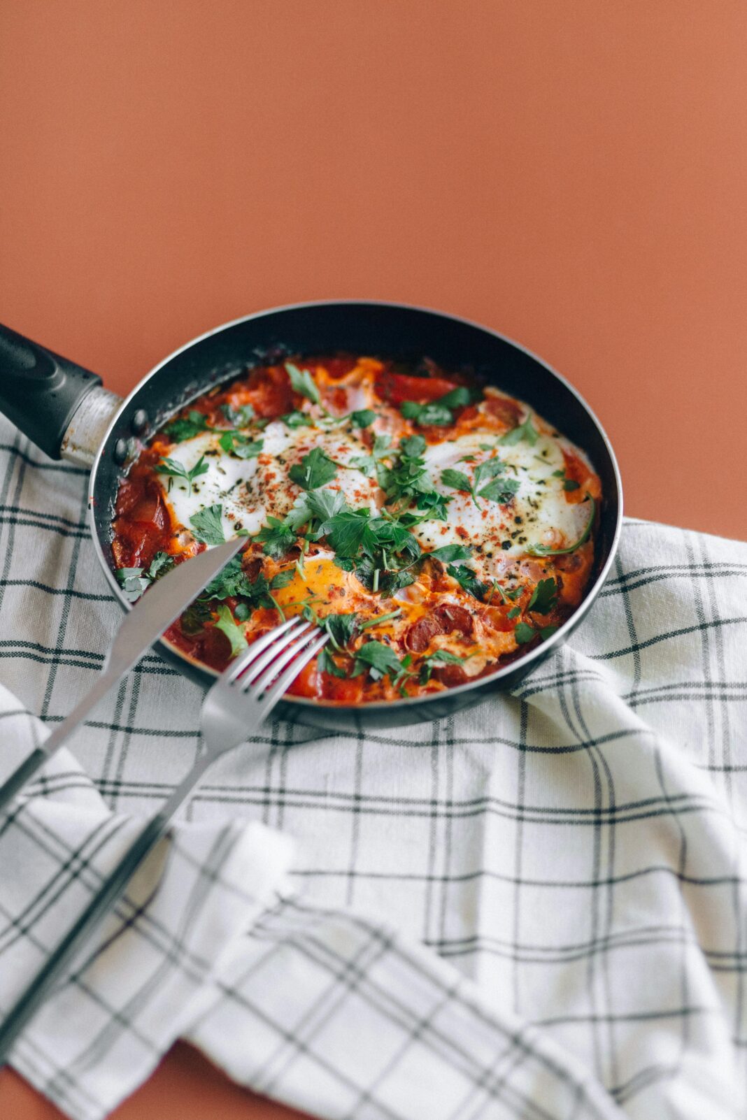 izrael Świeża shakshuka na patelni z ziołami na stole.