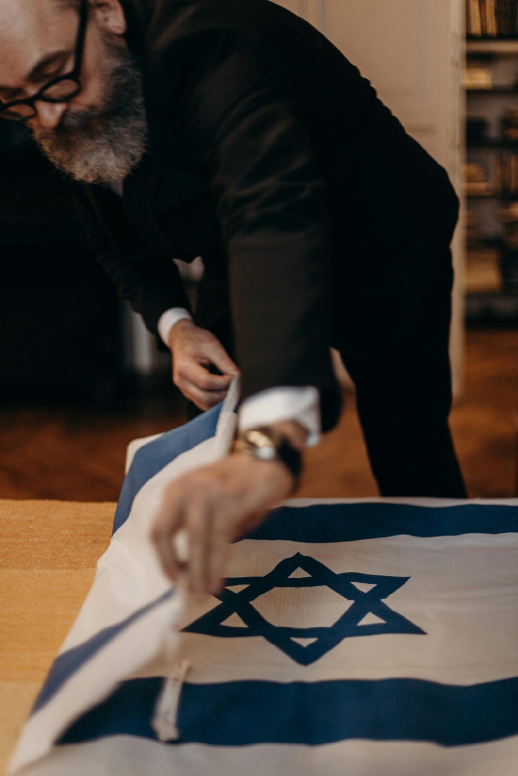 izrael Brodaty mężczyzna składający izraelską flagę w pomieszczeniu, skupiając się na tradycji i symbolice.