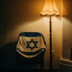 Relacje Izrael – USA – partnerstwo strategiczne Ciepło oświetlony pokój z izraelską flagą zawieszoną na fotelu.