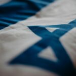 Kibuce – czym są i jak funkcjonują w XXI wieku Fragment izraelskiej flagi narodowej podkreślający Gwiazdę Dawida, podkreślający jej znaczenie kulturowe.