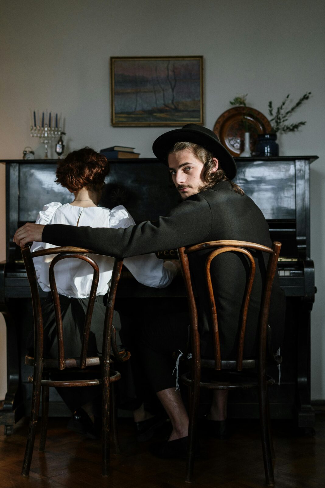 Para siedząca razem przy fortepianie, przywołująca miłość i muzykę w przytulnym domowym otoczeniu.