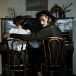 Para siedząca razem przy fortepianie, przywołująca miłość i muzykę w przytulnym domowym otoczeniu.