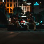 Dwóch muzyków gra na gitarach na nocnej ulicy w Ejlacie w Izraelu, tworząc tętniący życiem miejski nastrój.