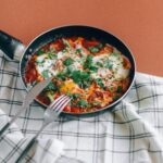 Świeża shakshuka na patelni z ziołami na stole. 