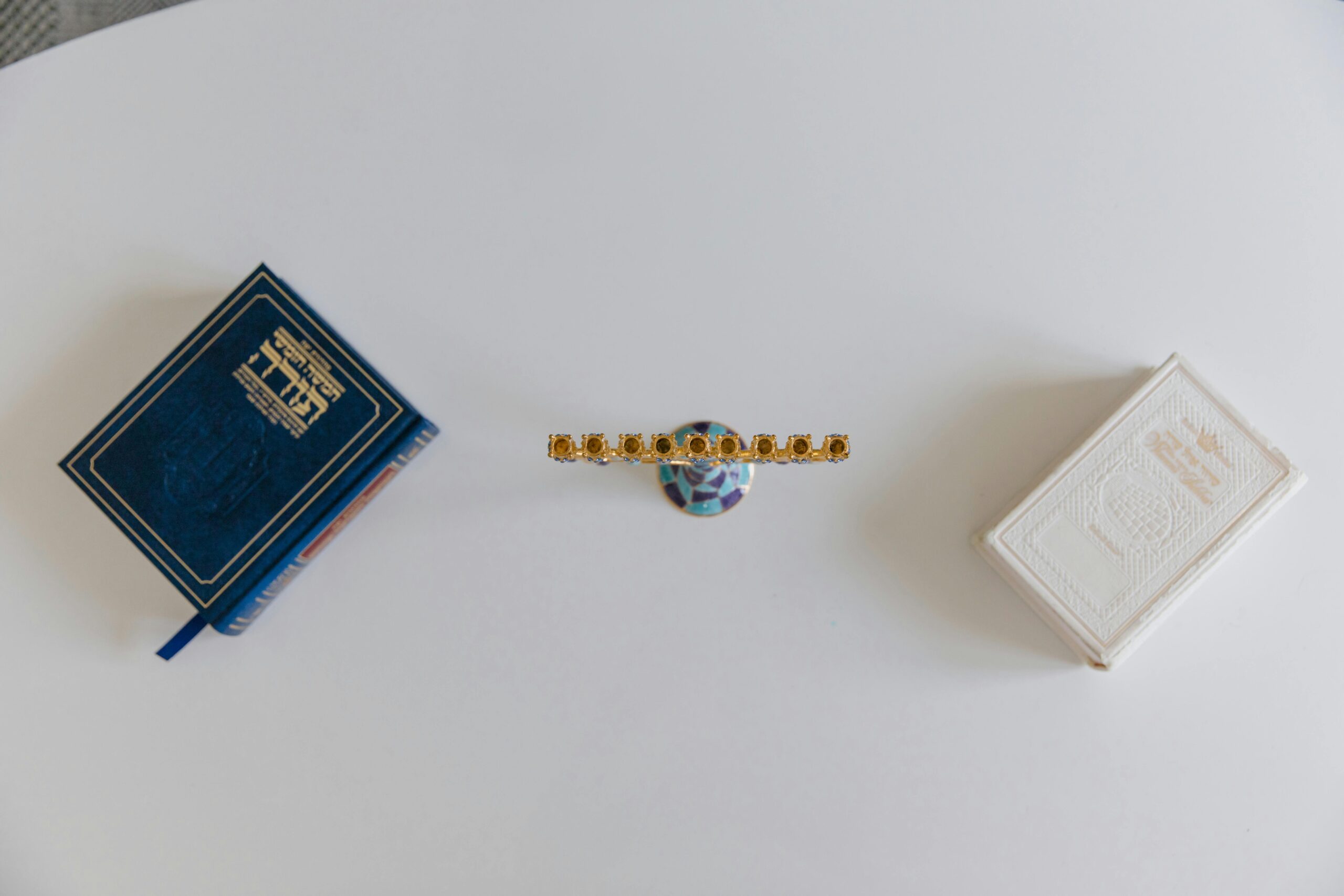 Widok z góry na menorę i księgi hebrajskie na białej powierzchni, symbolizujące kulturę żydowską.