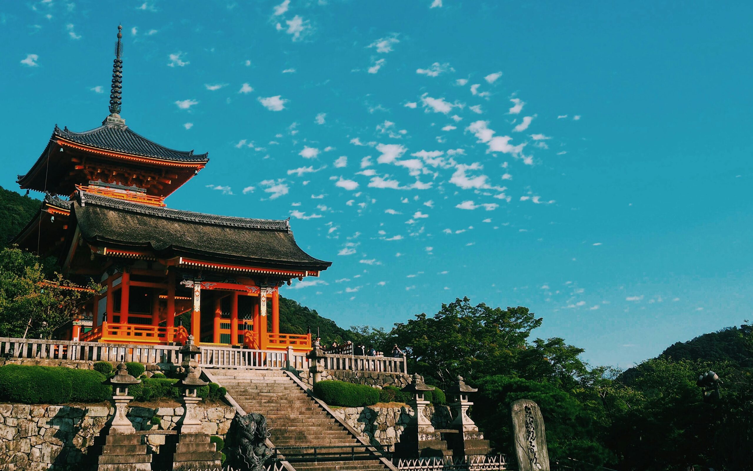 Piękny widok na świątynię Kiyomizu Dera w Kioto, prezentujący tradycyjną japońską architekturę pod tętniącym życiem niebem.