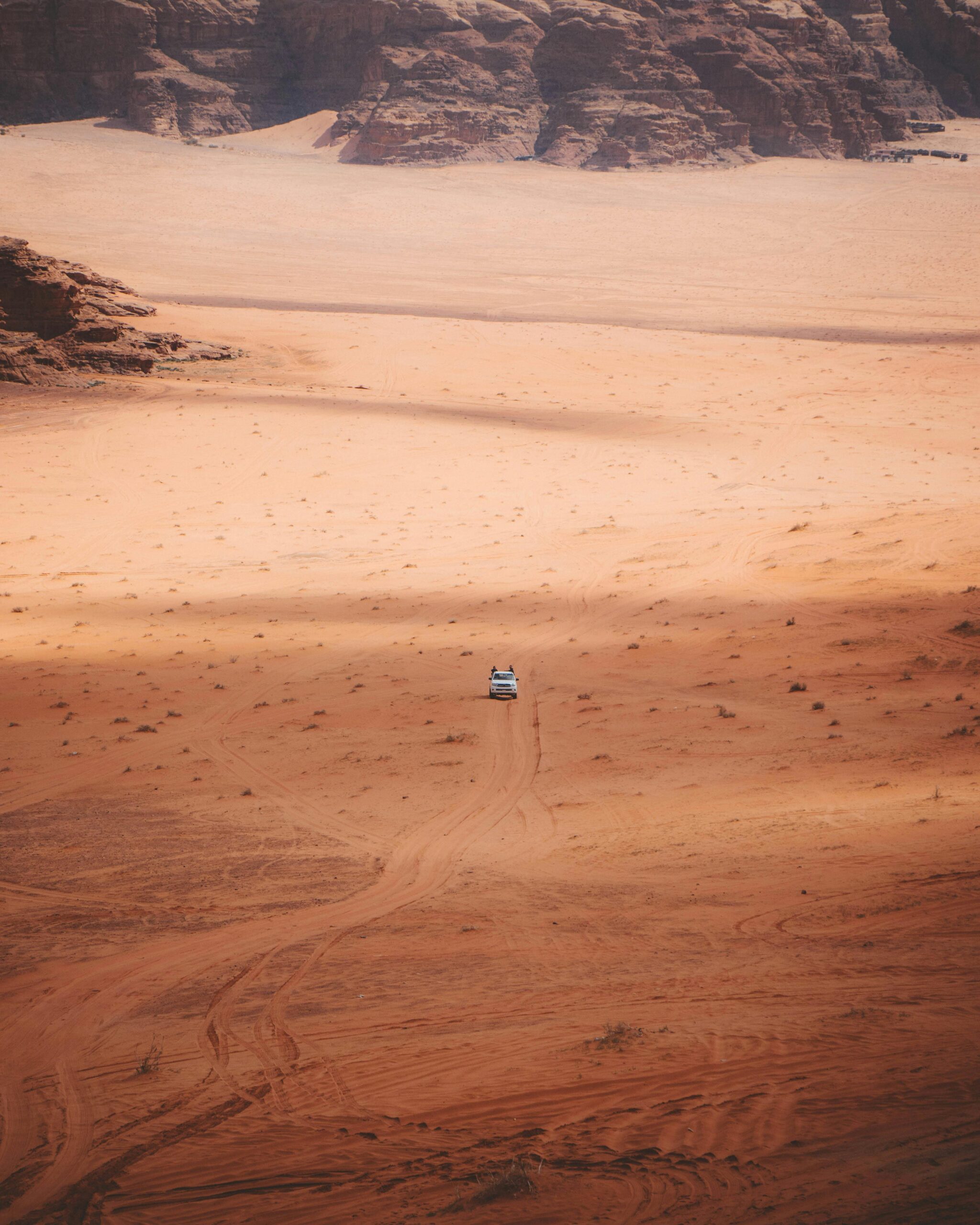 Widok z lotu ptaka na samotny samochód na polnej drodze na rozległej pustyni Wadi Rum w Jordanii.
