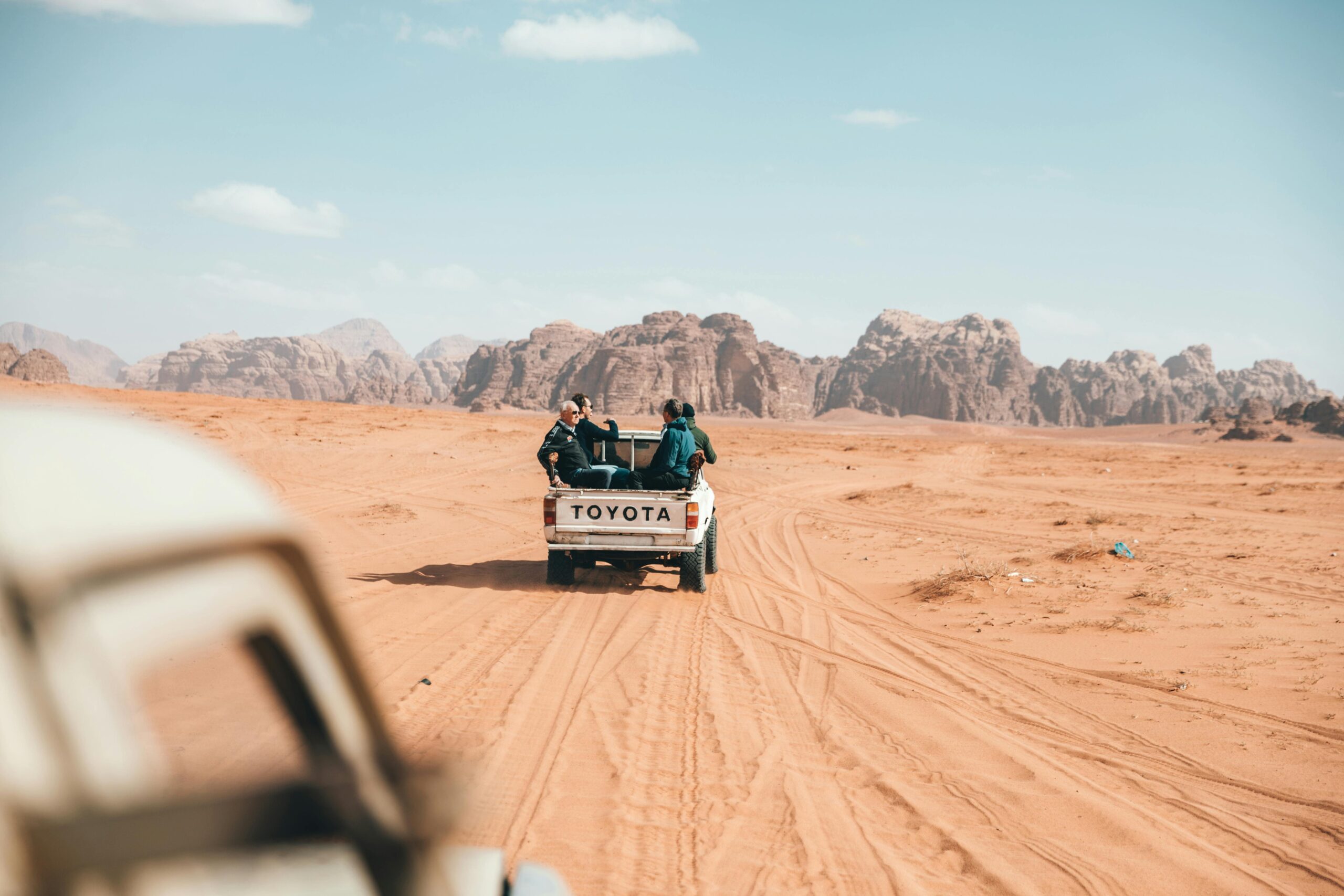 Pickup z podróżnikami jeżdżącymi po pustyni Wadi Rum, ukazujący esencję przygody w Jordanii.