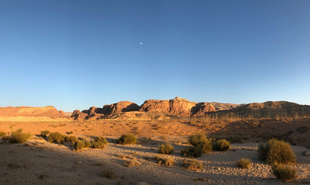 Piękna scena pustynna w Wadi Araba w Jordanii, przedstawiająca skalisty teren z czystym, błękitnym niebem.