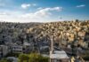 Widok z lotu ptaka na miejski krajobraz Ammanu z powiewającą flagą Jordanii.