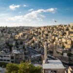 Festiwale i wydarzenia kulturalne w Jordanii Widok z lotu ptaka na miejski krajobraz Ammanu z powiewającą flagą Jordanii.